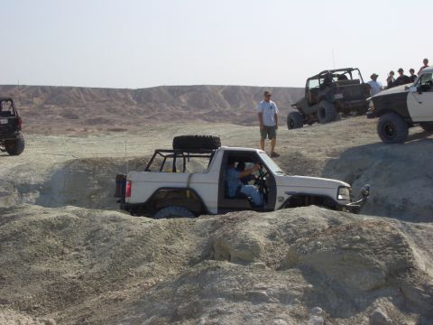 1985 Ford Bronco - Off-road vehicles tackle challenging terrain in a desert landscape.