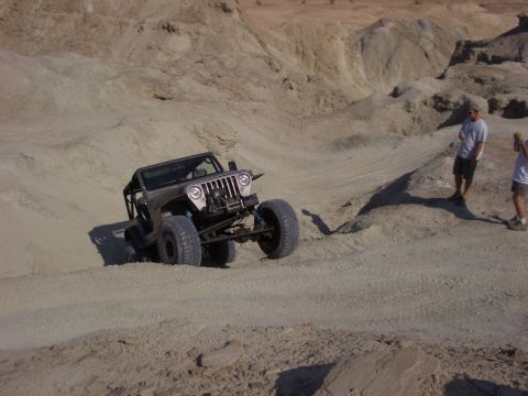 1985 Ford Bronco - A heavily modified Jeep Wrangler navigates a challenging off-road terrain.