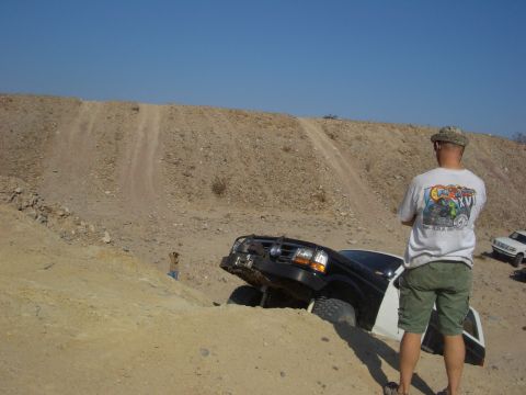 1985 Ford Bronco - A black and white SUV is stuck in the dirt while another vehicle waits behind it.