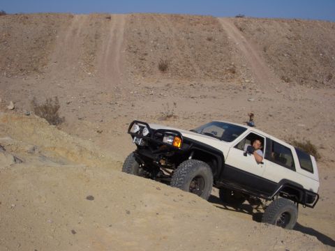 1985 Ford Bronco - Modified Toyota 4Runner navigates a steep, sandy trail in an off-road park.