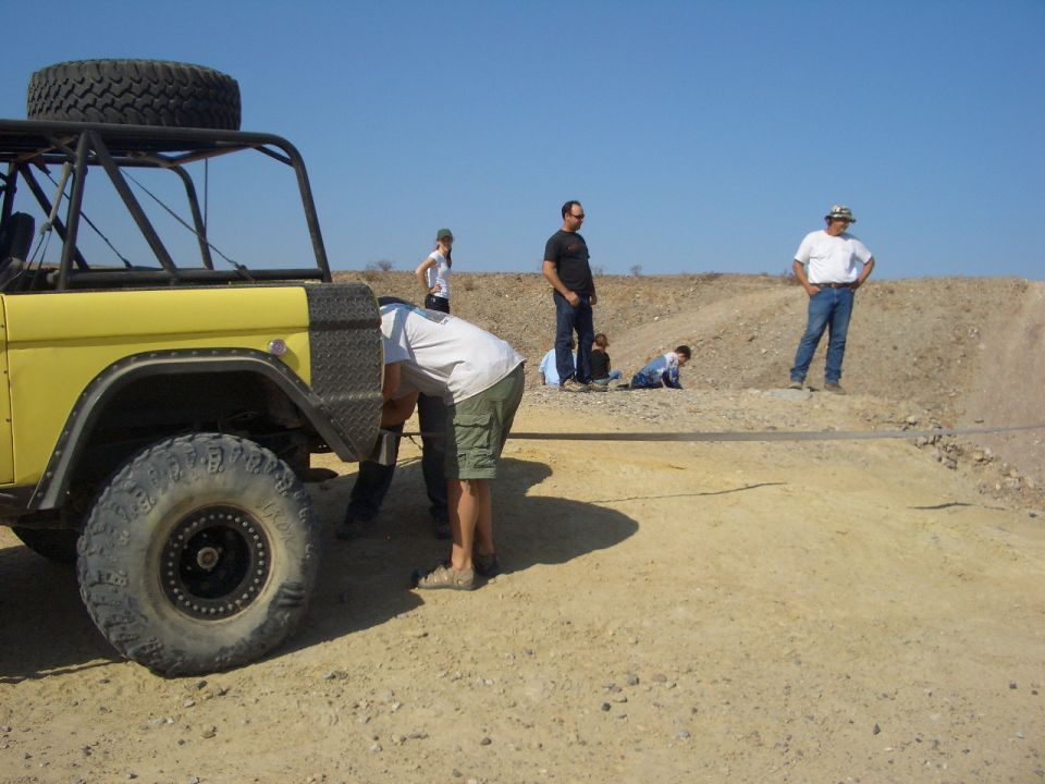 Yellow off-road vehicle with a spare tire on top, seen from the front quarter angle in a desert landscape