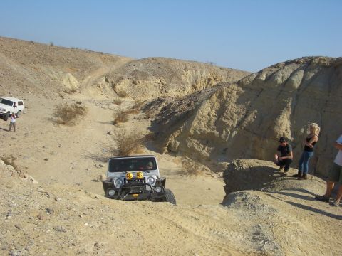1985 Ford Bronco - Off-roading adventure in a desert landscape with multiple vehicles and people.