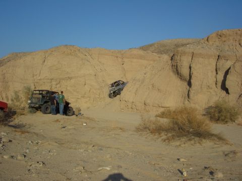 1985 Ford Bronco - Off-road vehicles navigate challenging sandy terrain on a clear day.