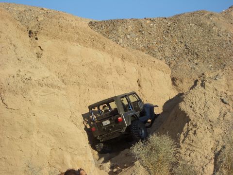 1985 Ford Bronco - A Jeep Wrangler navigates a challenging off-road trail in a desert canyon.