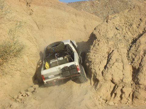 1985 Ford Bronco - Off-road truck carefully maneuvers through a tight, dusty canyon passage.