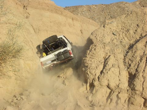 1985 Ford Bronco - Off-road vehicle navigates a steep, dusty canyon trail.
