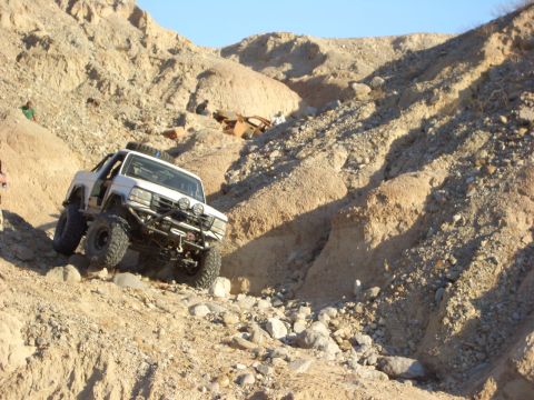 1985 Ford Bronco - This modified SUV navigates a steep, rocky incline in a desert landscape.