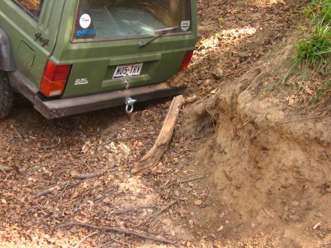 2001 Jeep Wrangler - This green Jeep Cherokee XJ is navigating a steep, dirt embankment with a fallen log.