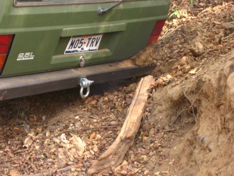 2001 Jeep Wrangler - The rear of a green SUV is partially obscured by dirt and foliage, with a visible license plate and tow hitch.