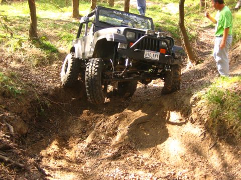 2001 Jeep Wrangler - A black Jeep Wrangler tackles a challenging off-road trail, with two people observing the action.