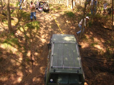 2001 Jeep Wrangler - People are using a winch to pull an off-road vehicle up a muddy incline in a wooded area.