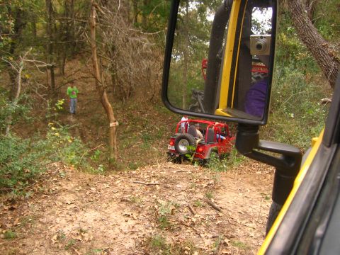 2001 Jeep Wrangler - Two Jeeps are seen on a wooded trail, one red and one yellow, with a person standing in the background.