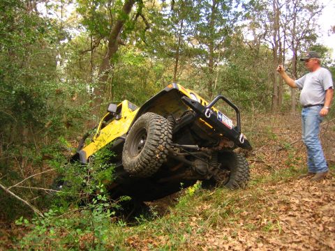 2001 Jeep Wrangler - A man photographs a yellow Jeep Wrangler that has tipped on its side while off-roading in a wooded area.