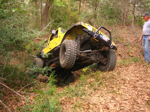2001 Jeep Wrangler - A yellow 2001 Jeep Wrangler navigates a steep, wooded incline, with its tires angled for maximum traction.