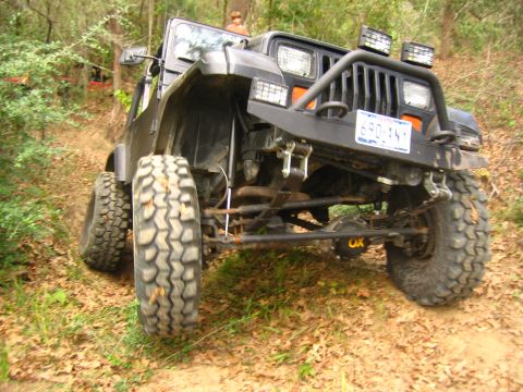 2001 Jeep Wrangler - A black Jeep Wrangler navigates an off-road trail with large tires and a modified front bumper.