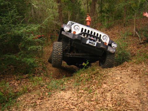 2001 Jeep Wrangler - A Jeep Wrangler navigates a steep, wooded trail with a person watching from the side.