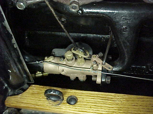 Carburetor mounted on an engine intake manifold with throttle linkage