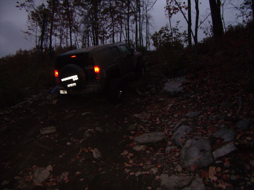 2003 Jeep Wrangler on a rocky, wooded trail at dusk