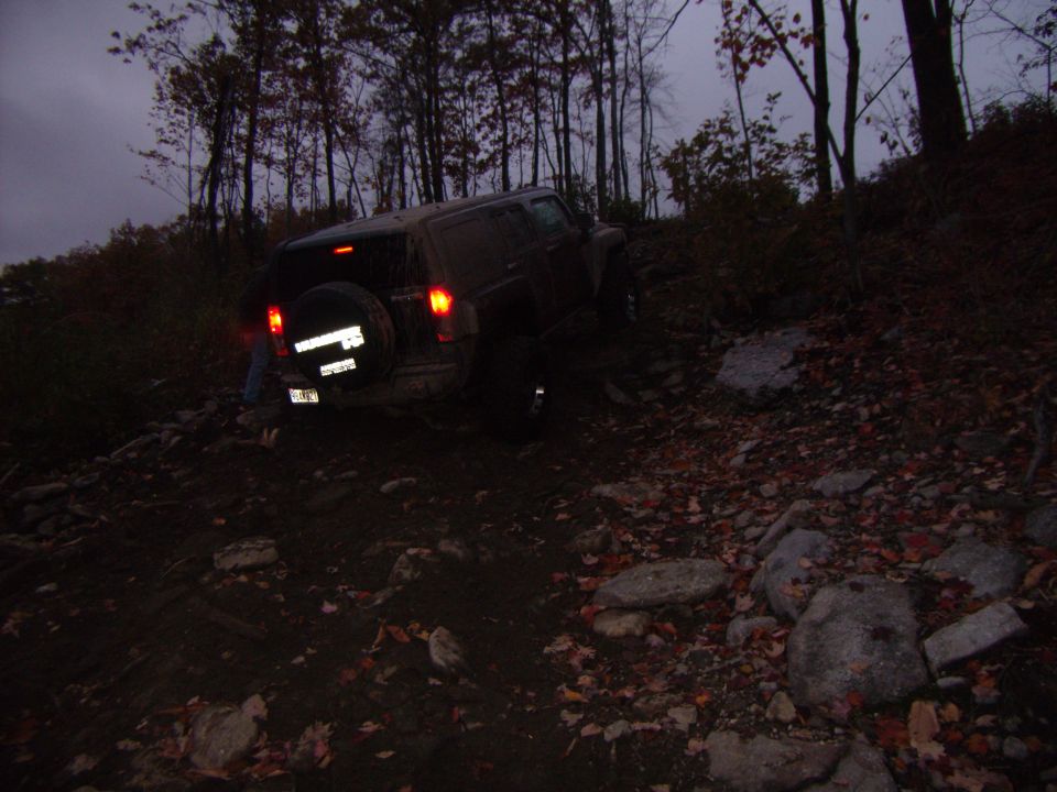 Hummer H3 on rocky trail, spare tire on back, taillights on
