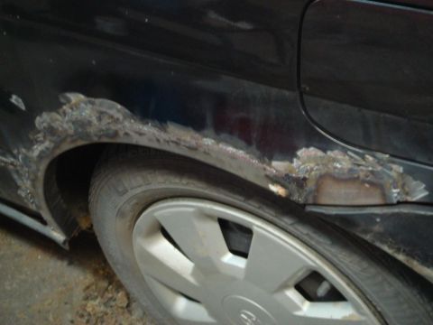 1996 Ford Bronco - Rust damage and repair work on the side of a black vehicle's rear wheel arch.
