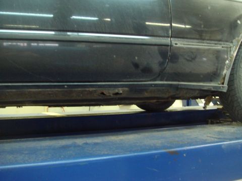 1996 Ford Bronco - Rusted rocker panel on a black car, showing significant corrosion.