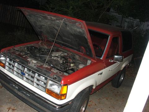 1989 Ford Bronco II - The 1989 Ford Bronco II is shown with its hood open, revealing the engine compartment.
