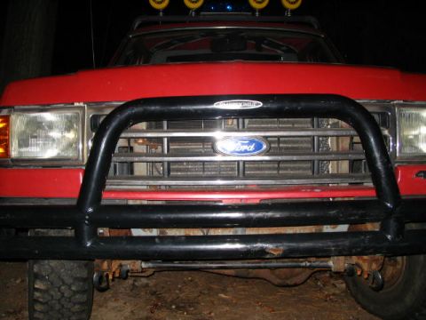 1989 Ford Bronco - Front view of a red Ford Bronco, likely from the late 1980s, equipped with a bull bar and auxiliary lights.