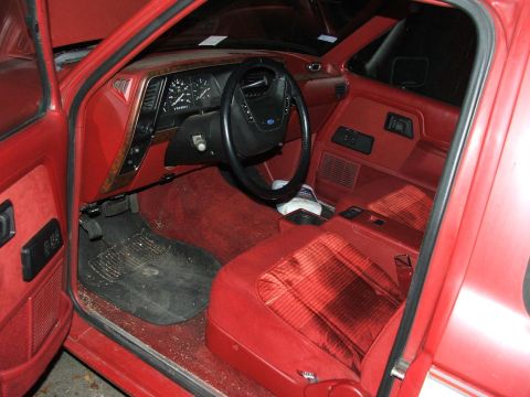 1989 Ford Bronco II - The interior of a red Ford Bronco II shows plaid seats and a dashboard with a steering wheel and gauges.