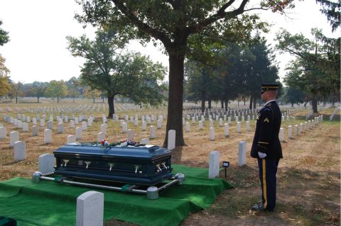 1991 Ford Bronco - A solemn scene unfolds in a military cemetery as a soldier stands at attention beside a coffin.