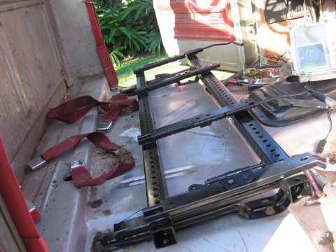 1979 Ford F-150 - The interior of a 1979 Ford F-150 shows exposed seat rails and red seatbelts, indicating a work in progress or restoration.