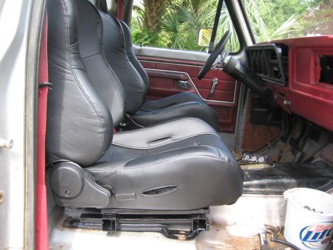 1979 Ford F-150 - The interior of a truck shows new black bucket seats and red door panels, with a view of the dashboard and steering wheel.