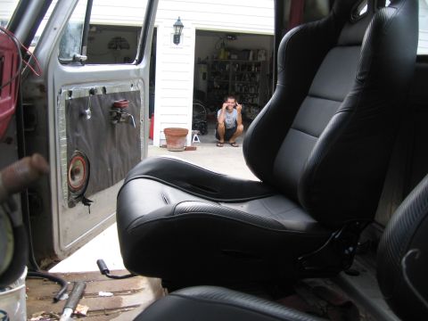 1979 Ford F-150 - Interior view of a vehicle's black racing seats, with the driver's side door open to reveal the interior.