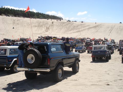 1979 Ford Bronco - A group of Ford Broncos and other vehicles gathered on a sandy dune area.
