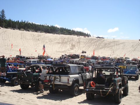 1979 Ford Bronco - A large gathering of off-road vehicles on a sandy terrain under a clear blue sky.