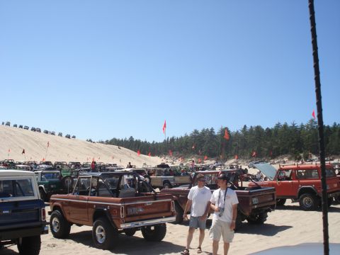 1979 Ford Bronco - A large gathering of Ford Broncos on a sandy terrain, with many vehicles and people visible under a clear blue sky.