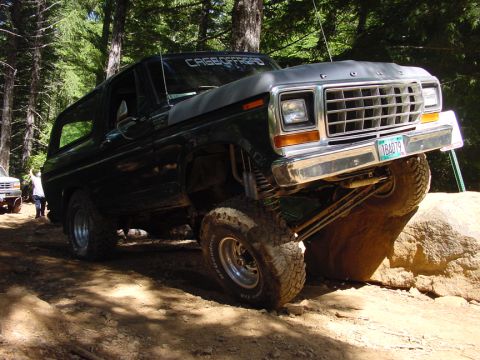 1979 Ford Bronco - A black Ford Bronco navigates a rocky off-road course, its lifted suspension clearly visible.