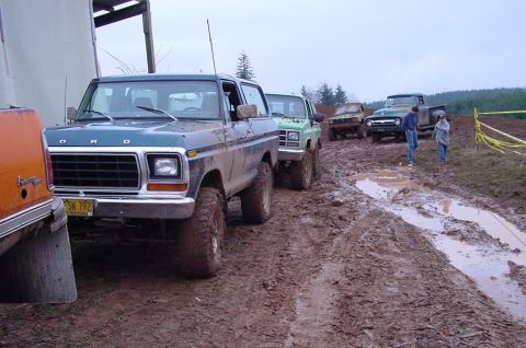 1979 Ford Bronco - Several off-road vehicles, including a Ford Bronco, navigate a muddy track.