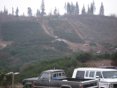 1979 Ford Bronco - Vehicles navigate muddy tracks on a hillside, kicking up dust.