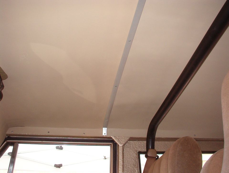 The headliner is painted & installed.  This is an aftermarket one, and its quality leaves something to be desired.  It's shipped rolled, and the creases weren't formed well enough.  The board almost broke when the edges were folded down for installation.  The predrilled screw holes in the aluminum strip aren't symmetric.  It was only available in a dull gray, requiring painting it this color (ultra-flat tan).  From certain angles, the paint is splotchy.