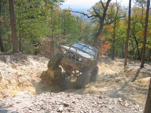 1992 Ford Mustang - A modified off-road vehicle tackles a challenging rocky path amidst autumn foliage.