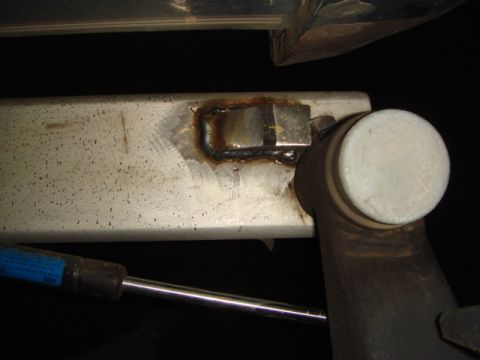 1996 Ford Bronco - Close-up of a welded metal bracket on a vehicle frame, with a gas strut visible.
