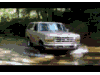 1996 Ford Bronco - A tan Ford Bronco navigates through a watery path surrounded by trees.
