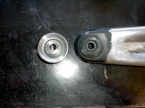 1996 Ford Bronco - Suspension part and roller bearing shown side-by-side on a dark surface.