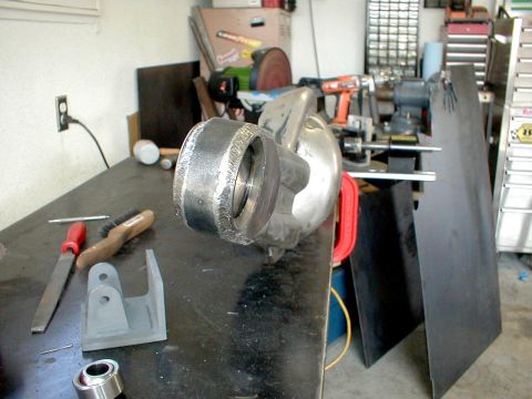 1996 Ford Bronco - A metal component, possibly for suspension, sits on a workbench with tools and equipment in the background.