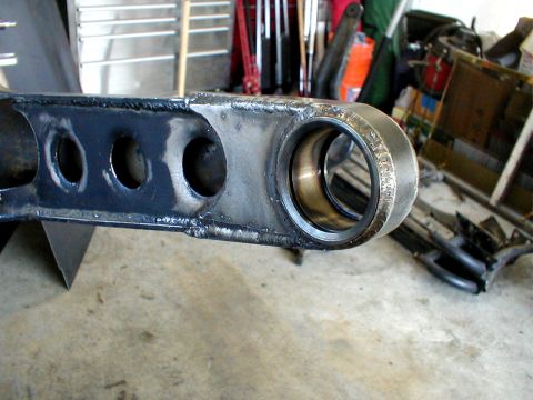 1996 Ford Bronco - A close-up view of a vehicle's suspension component, a dark metal construction with visible cutouts and a brass bushing.
