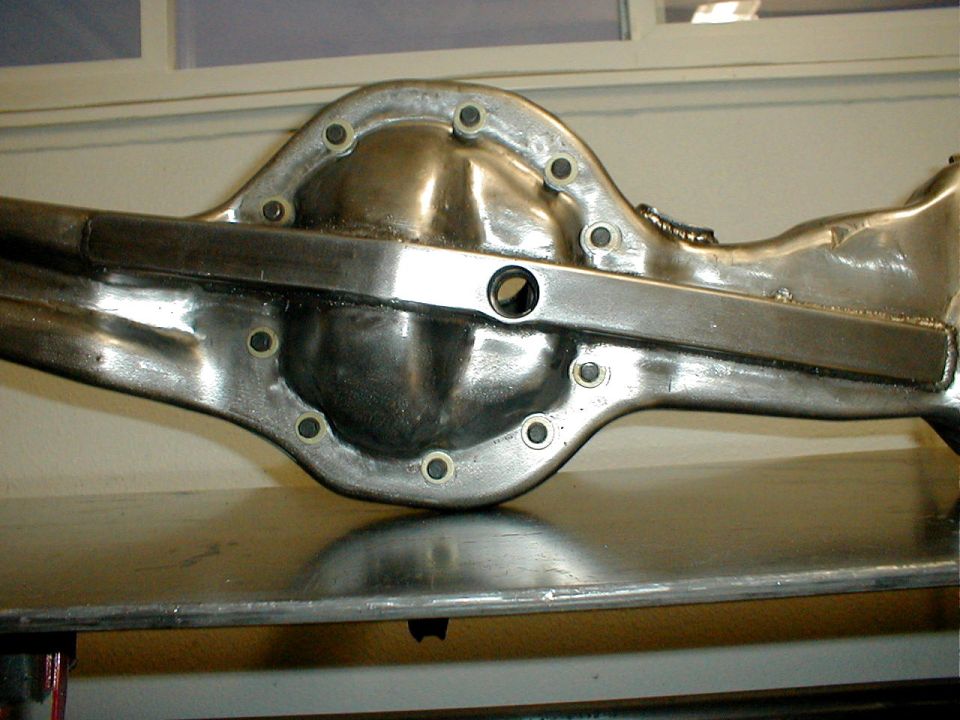Differential housing with a metal bar attached, showing bolts and a central hole