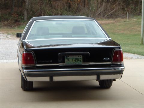 1989 Ford Crown Victoria LTD - The rear of a black 1989 Ford Crown Victoria LTD is parked on a concrete driveway.