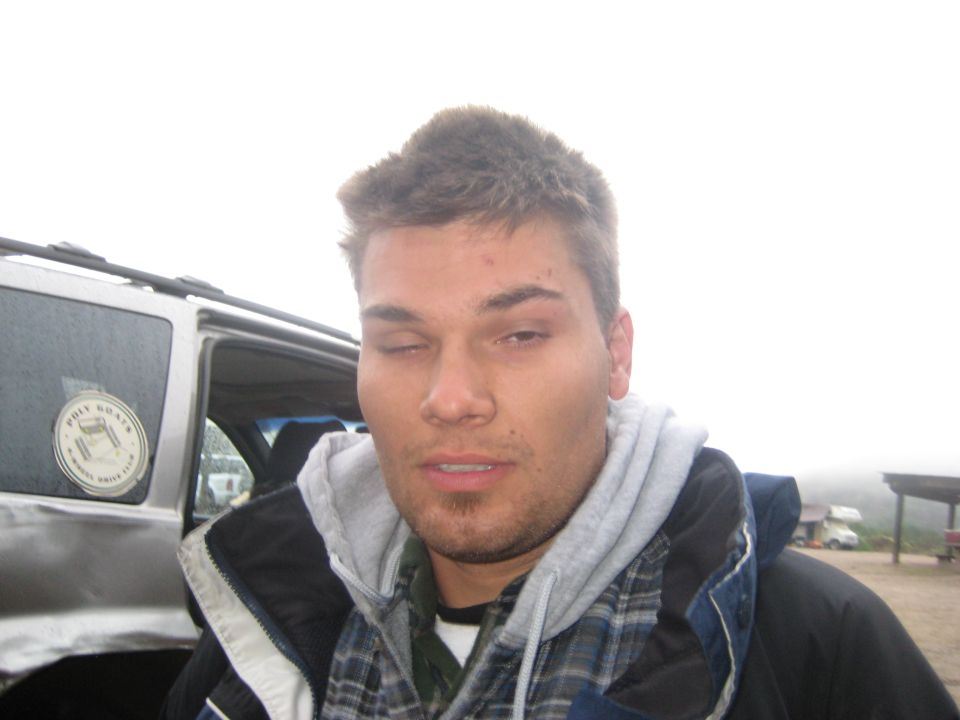 guy winks at camera, SUV behind him