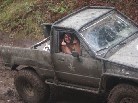 1966 Jeep CJ5 - A muddy pickup truck with a roll cage is driven off-road by a person showing their middle fingers.