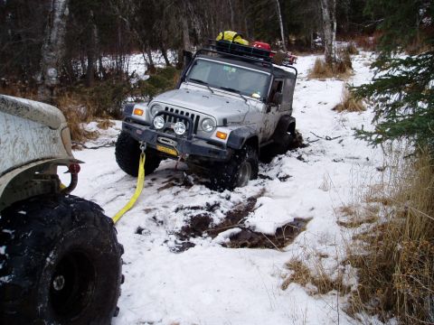 2000 Ford E350 - Two off-road vehicles in a snowy wooded area, one Jeep Wrangler is stuck and being pulled by another vehicle.